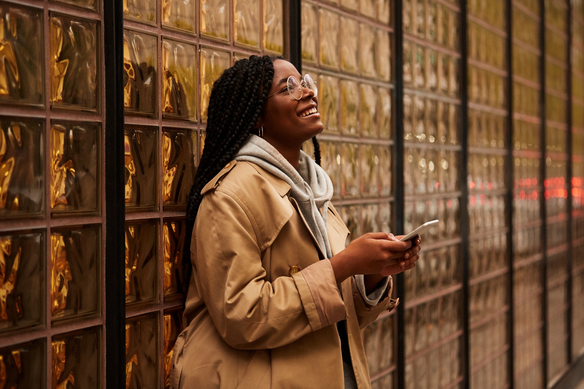 African American woman using smartphone near glass wall